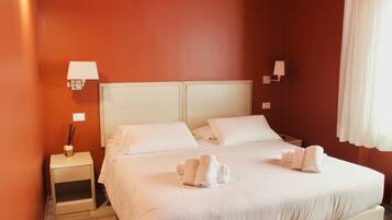 Una habitación de hotel con una cama grande, dos mesitas de noche y dos lámparas de pared.