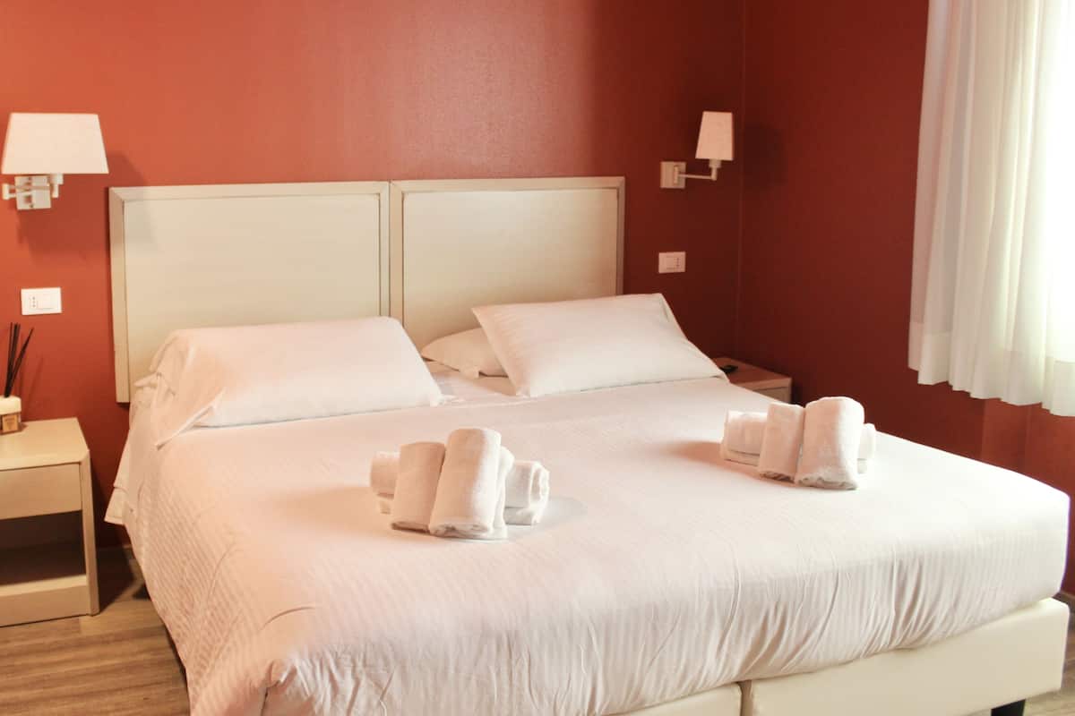 A hotel room with a double bed, two bedside tables, and a nightstand.
