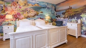 A bedroom with a large bed, two bedside tables, and a colorful mural on the wall.