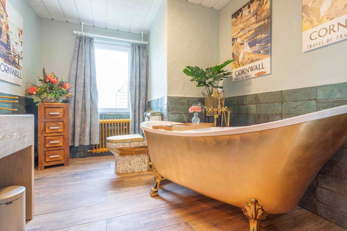 A bathroom with a freestanding bathtub, wooden cabinets, a radiator, and a window with curtains.
