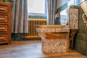 A bathroom with a patterned toilet, wooden cabinet, and radiator.