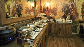 A buffet setup with various food items, serving utensils, and a large mirror reflecting the room's decor.