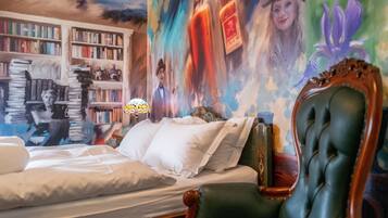 Quarto com uma cama grande, uma poltrona verde, uma estante e um mural na parede.