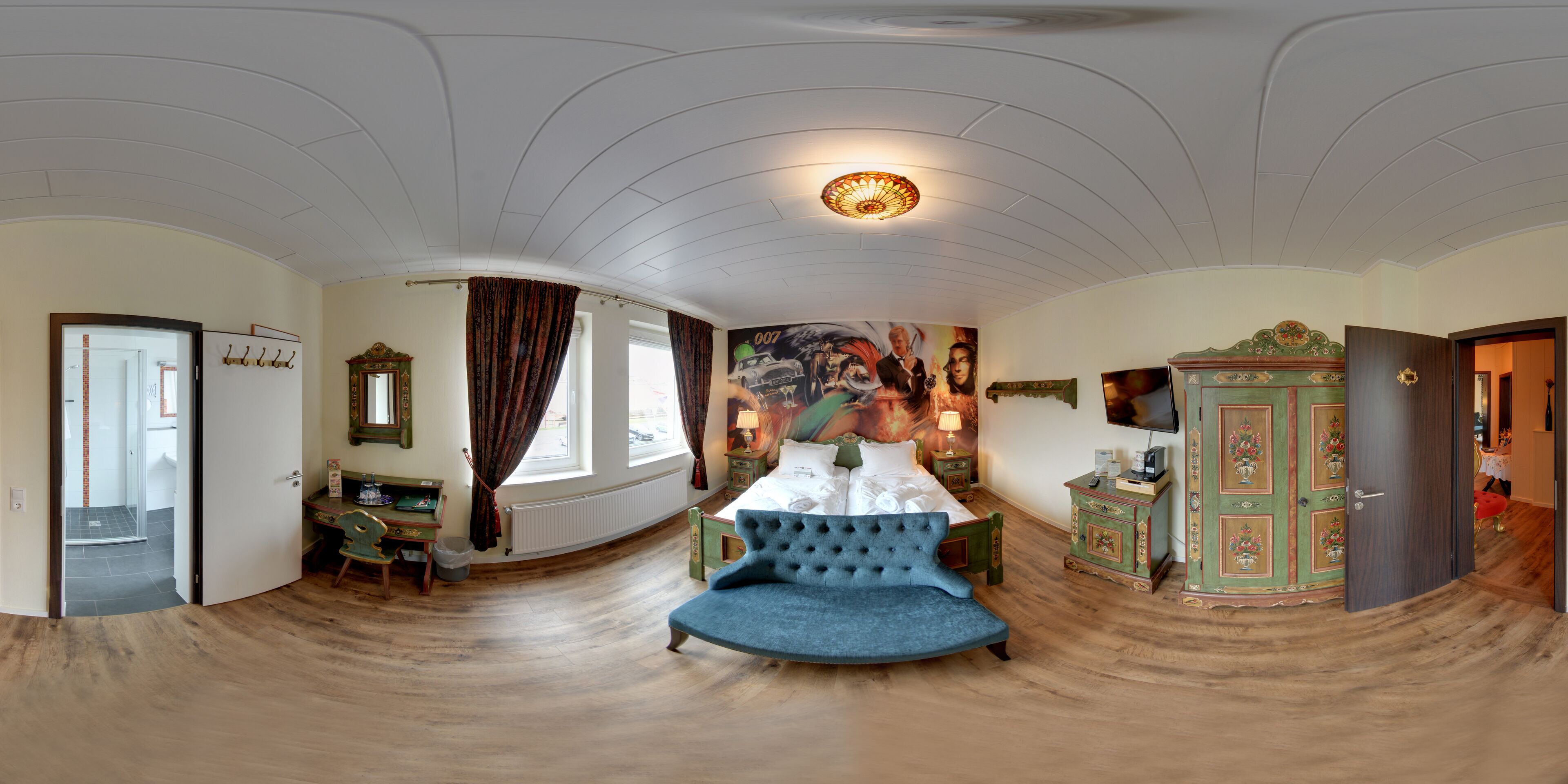 A room with a bed, a blue sofa, a wooden cabinet, and a large window with curtains.