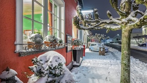 A snow-covered street with a building featuring large windows and a red exterior.
