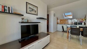 Een moderne woonkamer met een flatscreen televisie, een salontafel en een boekenkast.