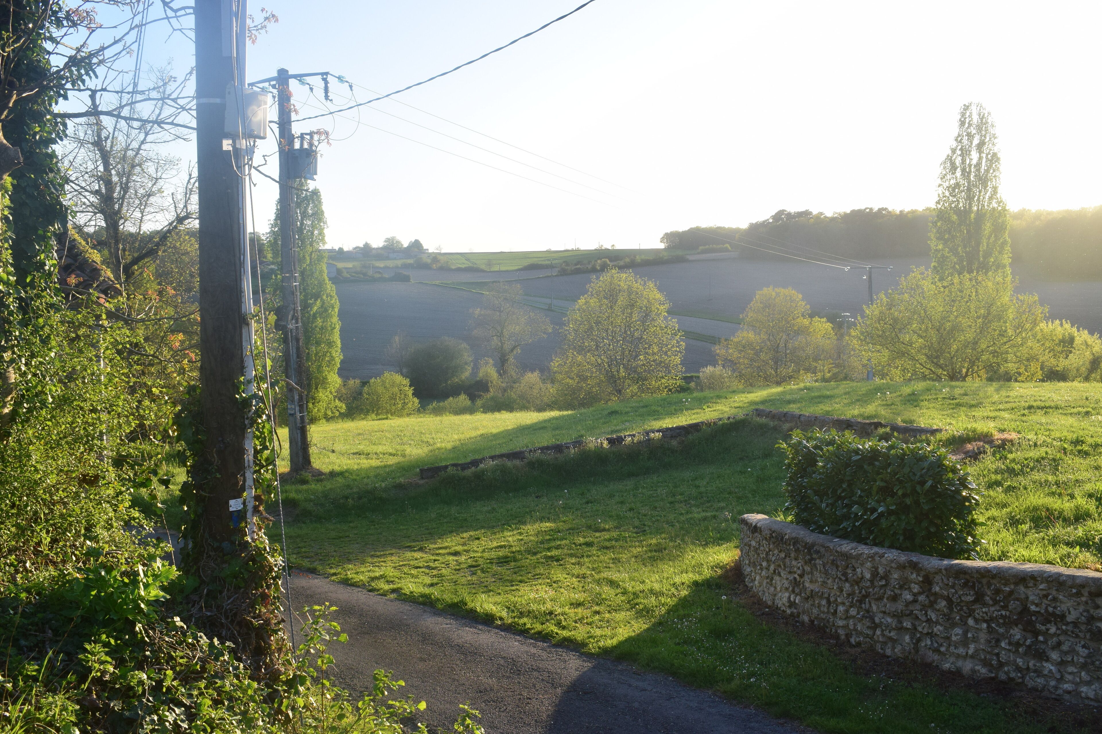 A rural landscape with a stone wall and a road.