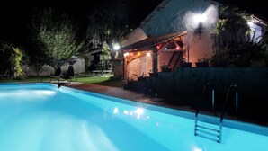 A swimming pool with a ladder, surrounded by a stone wall and a small building with outdoor lighting. - Entire Cosy cottage with pool idyllic location close to Aubeterre AMAZING VALUE! (Saint-Romain)