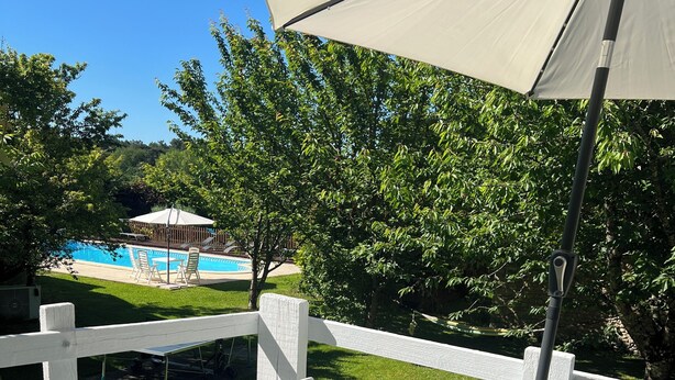 A patio with white furniture, a pool, and a view of a building in the background. - Entire Cosy cottage with pool idyllic location close to Aubeterre AMAZING VALUE! (Saint-Romain)