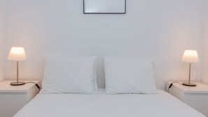 Ein schlichter, sauberer Raum mit einem Bett, zwei Nachttischen und zwei Lampen.