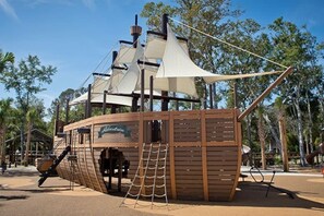 A wooden pirate ship structure with a rope ladder and a sign that reads 'Adventure.'