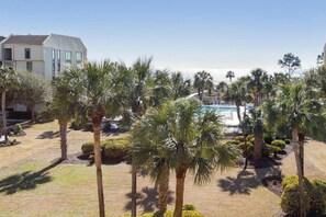 A pool area with palm trees, a building with large windows, and a clear sky.
