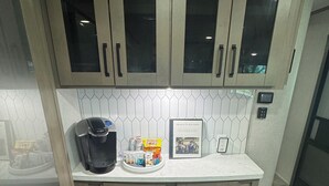 A compact kitchen with wooden cabinets, a coffee maker, and a small breakfast tray.