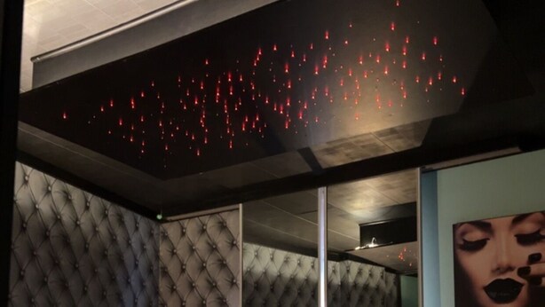 Un dormitorio con cama, espejo y una pared con luces rojas.