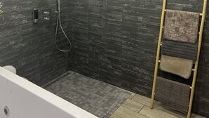 Un baño moderno con bañera, ducha y un perchero con varias toallas.