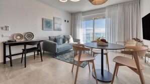 Un salon moderne comprenant un canapé, une table à manger avec des chaises, une grande fenêtre avec des rideaux et un luminaire suspendu.
