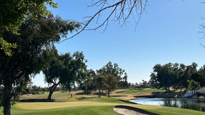 A golf course with a pond, trees, and a clear sky. - Water/Golf Course Backyard | Heated Pool Included in Price | Modern 3 bedroom (Chandler)