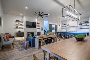 A spacious living area with a fireplace, a dining table, and a kitchen area with bar stools.