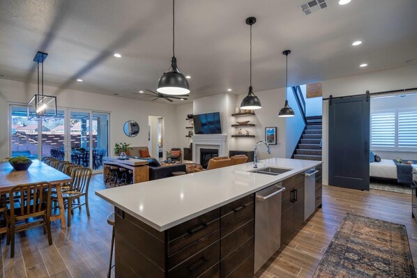A modern kitchen with a large island, built-in appliances, and pendant lighting.