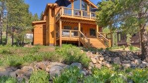 A wooden cabin with a balcony, surrounded by a rocky landscape and trees. - Streams and Dreams - TLUXP (Truckee)