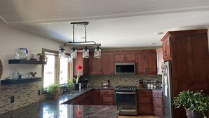 Una cocina moderna con encimeras de granito, gabinetes de madera, un refrigerador de acero inoxidable y un horno empotrado.