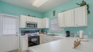 A kitchen with white cabinets, a microwave, a coffee maker, and a sink.