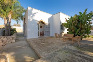 A white building with a stone wall and a paved patio area. - 3156 Villa Andrea House by Barbarhouse (Porto Cesareo)