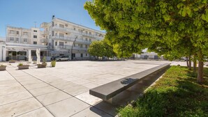 A spacious outdoor area with a long bench, potted plants, and a building with multiple floors and balconies in the background. - 2345 Le Due Torri - Torre Grande by Barbarhouse (Melendugno)
