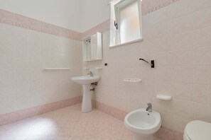 A bathroom with a pedestal sink, a bidet, a toilet, and a mirror. - 2345 Le Due Torri - Torre Grande by Barbarhouse (Melendugno)