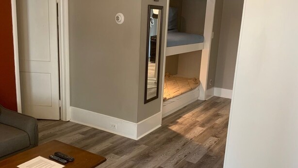 Una habitación con una cama alta, un sofá, una mesita de centro y una puerta.