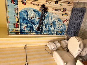 Een badkamer met een gestreepte vloer, een wit toilet, een handdoekhouder en een douchegordijn met een blauw patroon.