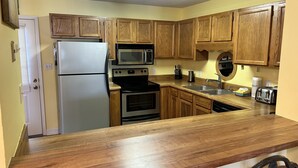 A kitchen with wooden cabinets, stainless steel appliances, a microwave, and a toaster.