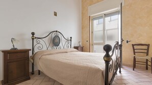 A bedroom with a bed, a nightstand, a chair, and a window. - 2344 Le Due Torri - Torre Piccola by Barbarhouse (Melendugno)