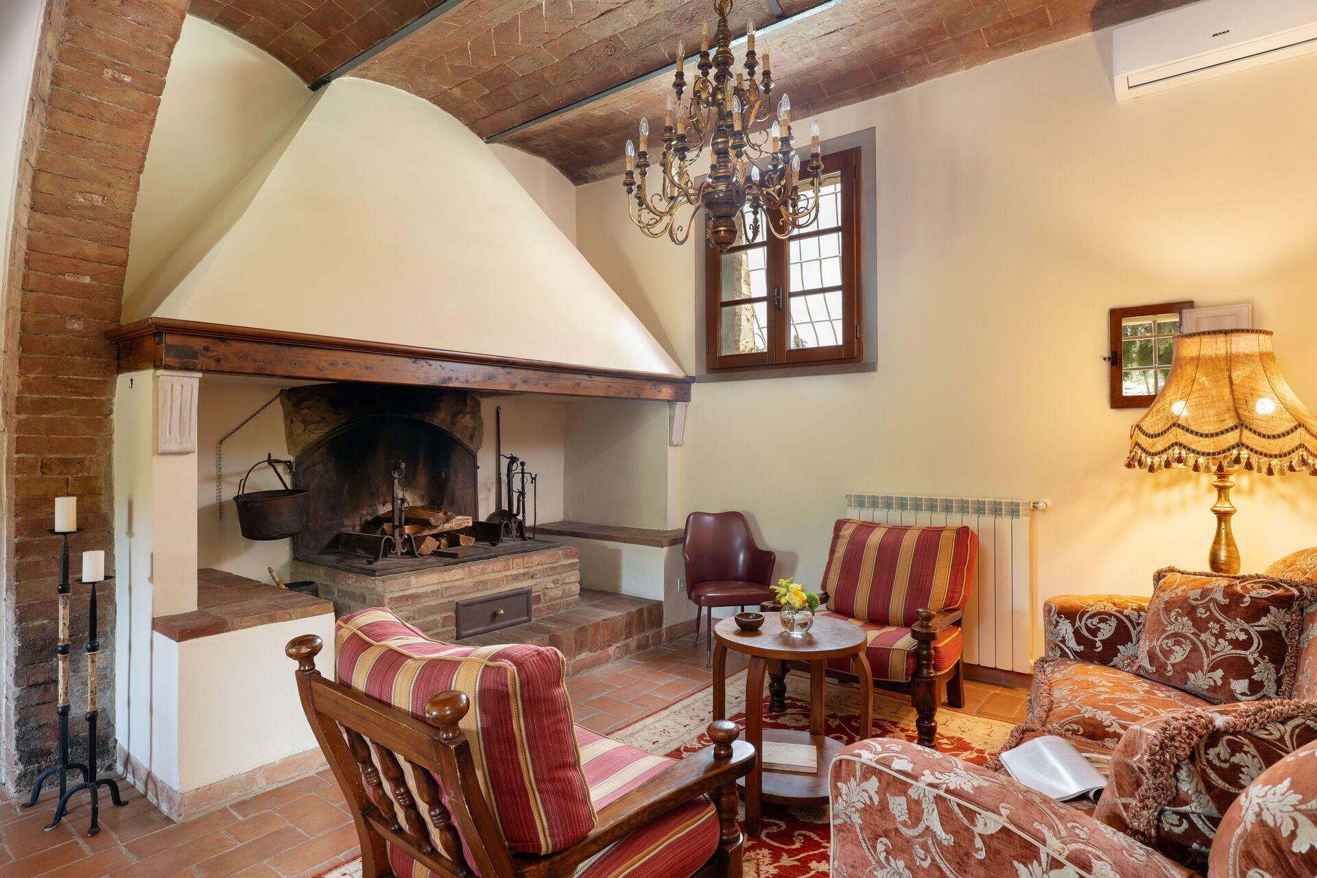 A cozy living room with a fireplace, a chandelier, and comfortable seating.