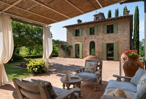 A covered patio with outdoor furniture, a stone building with green shutters, and a garden with potted plants. - Villa in Pillo with 7 bedrooms sleeps 14 (Pillo)