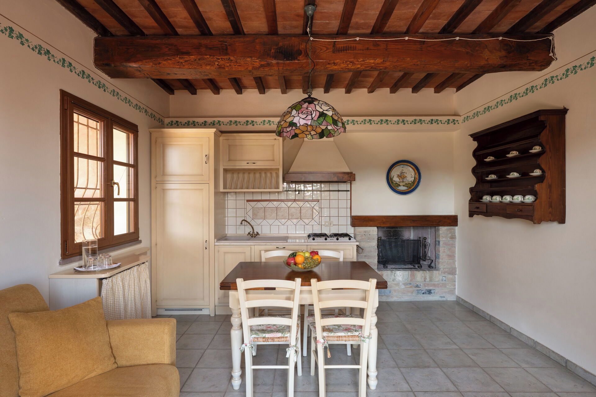 A kitchen with a dining table, chairs, a hanging light fixture, and a fireplace.