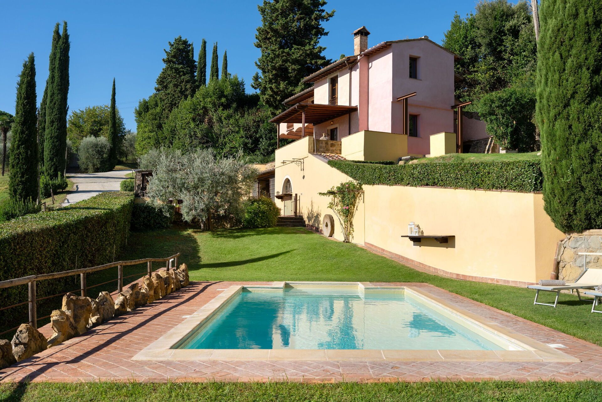 A residential property with a swimming pool, a well-maintained garden, and a two-story house.