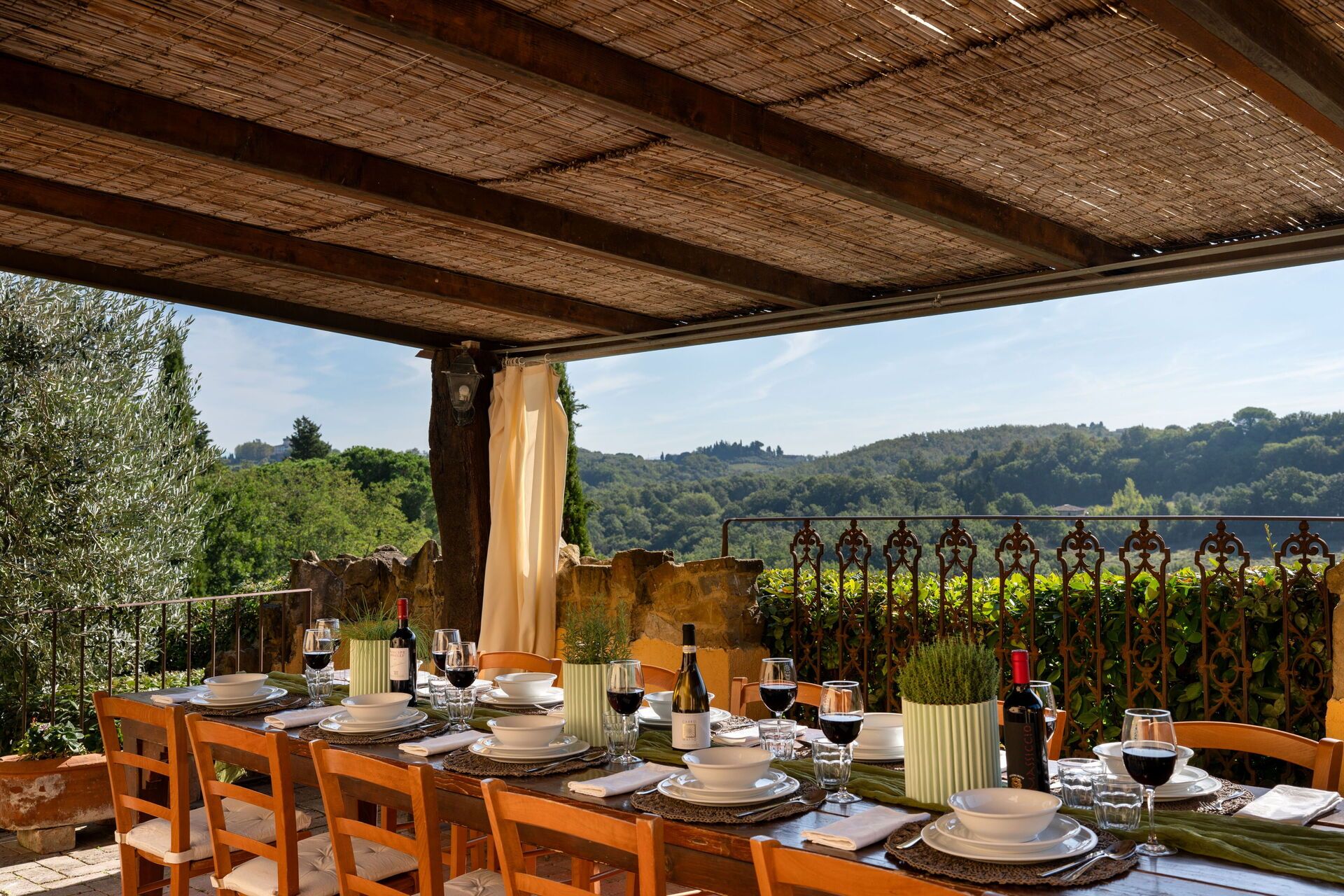 Un área de comedor al aire libre con una mesa preparada para una comida, con vista a un paisaje boscoso.