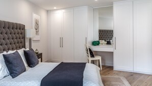 A modern bedroom with a large bed, a desk, and a wardrobe. - Modern Family Home in Kensington (London)