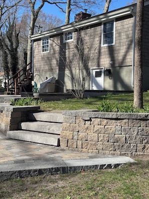 Une maison avec un escalier en pierre, un mur en briques et un petit jardin.