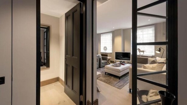 A modern living room with a sofa, a TV, and a coffee table. - 4-bedroom Apartment in the Heart of Chelsea (London)