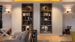 A modern living room with a sofa, a coffee table, and two wall-mounted shelves with decorative items. - 4-bedroom Apartment in the Heart of Chelsea (London)