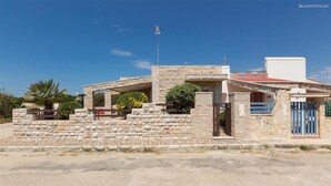 Una casa in pietra con tetto in tegole rosse, un'antenna parabolica e un cancello.