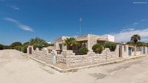 Un edificio in pietra con tetto piatto, un'antenna e un vialetto lastricato.