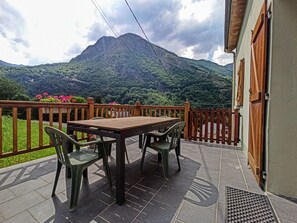 Une terrasse avec une table et des chaises en bois, une vue sur une montagne et une clôture en bois.