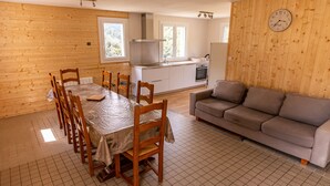 Un comedor con una mesa y sillas de madera, una cocina con estufa y horno, y un sofá gris.