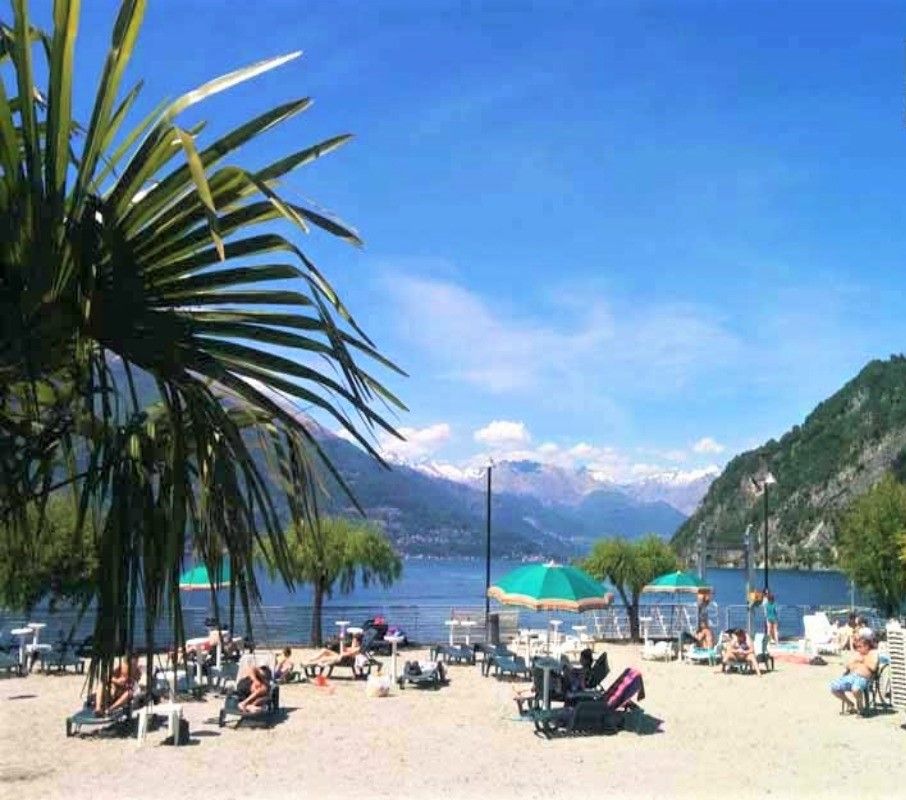 A beach with sun loungers, umbrellas, and a mountainous backdrop.