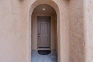 A hallway leading to a door with a doormat.