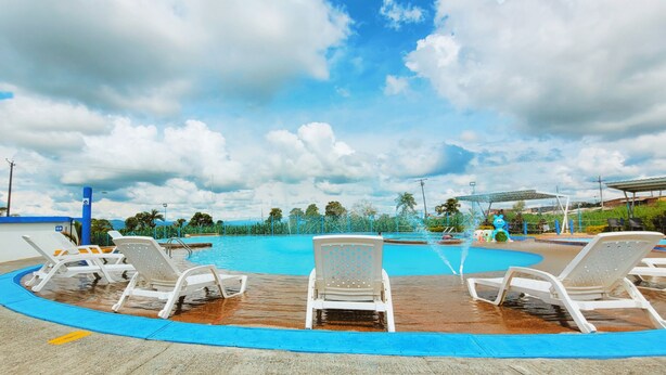 A swimming pool with white lounge chairs and a water fountain. - Apartment 5 minutes from the Coffee Park, near Panaca, Salento, Cocora. (Montenegro)