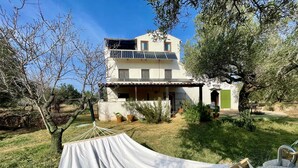 A two-story house with a balcony, surrounded by trees and a hammock in the foreground. - MAS GINJOL (Tortosa)